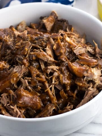 A bowl of Instant Pot pulled pork drizzled with BBQ sauce.