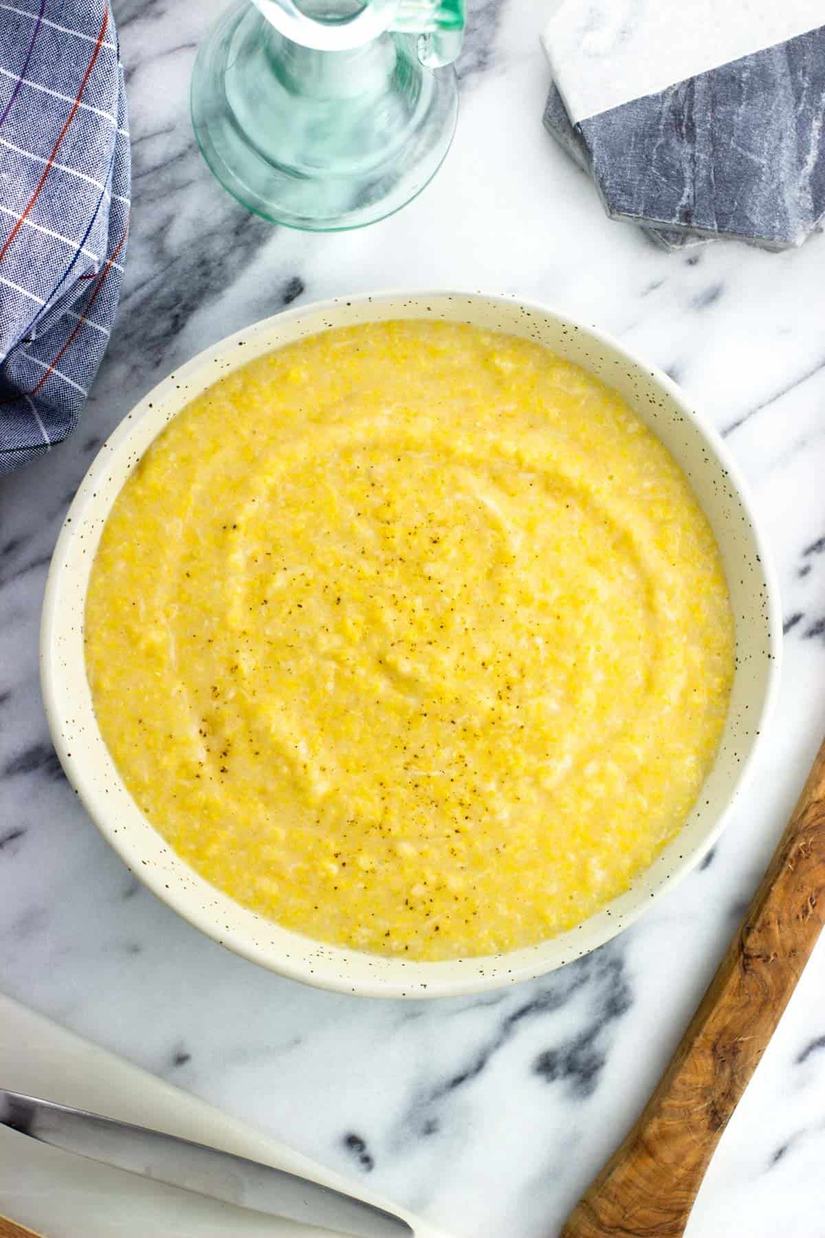 A bowl of creamy polenta garnished with fresh cracked pepper.