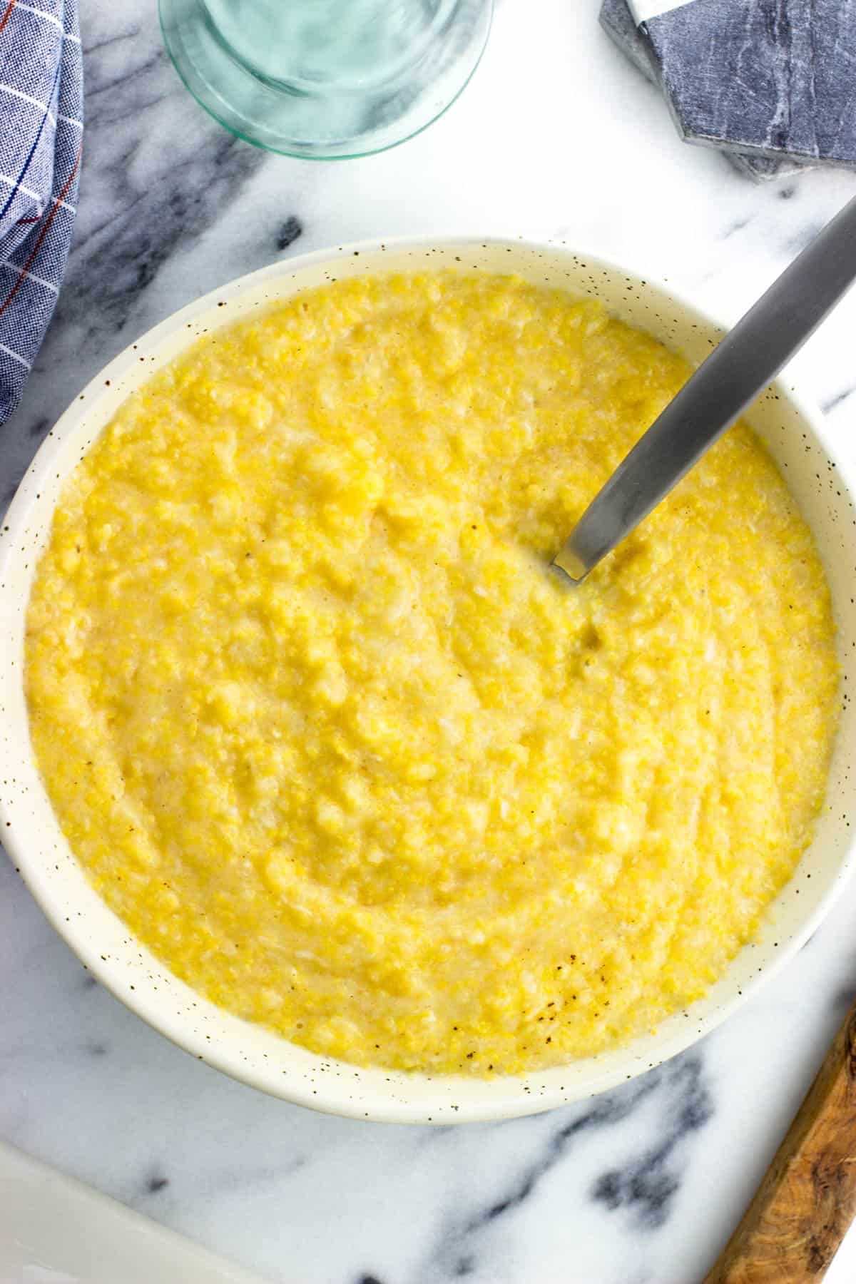 A bowl of creamy polenta with a serving spoon in it.