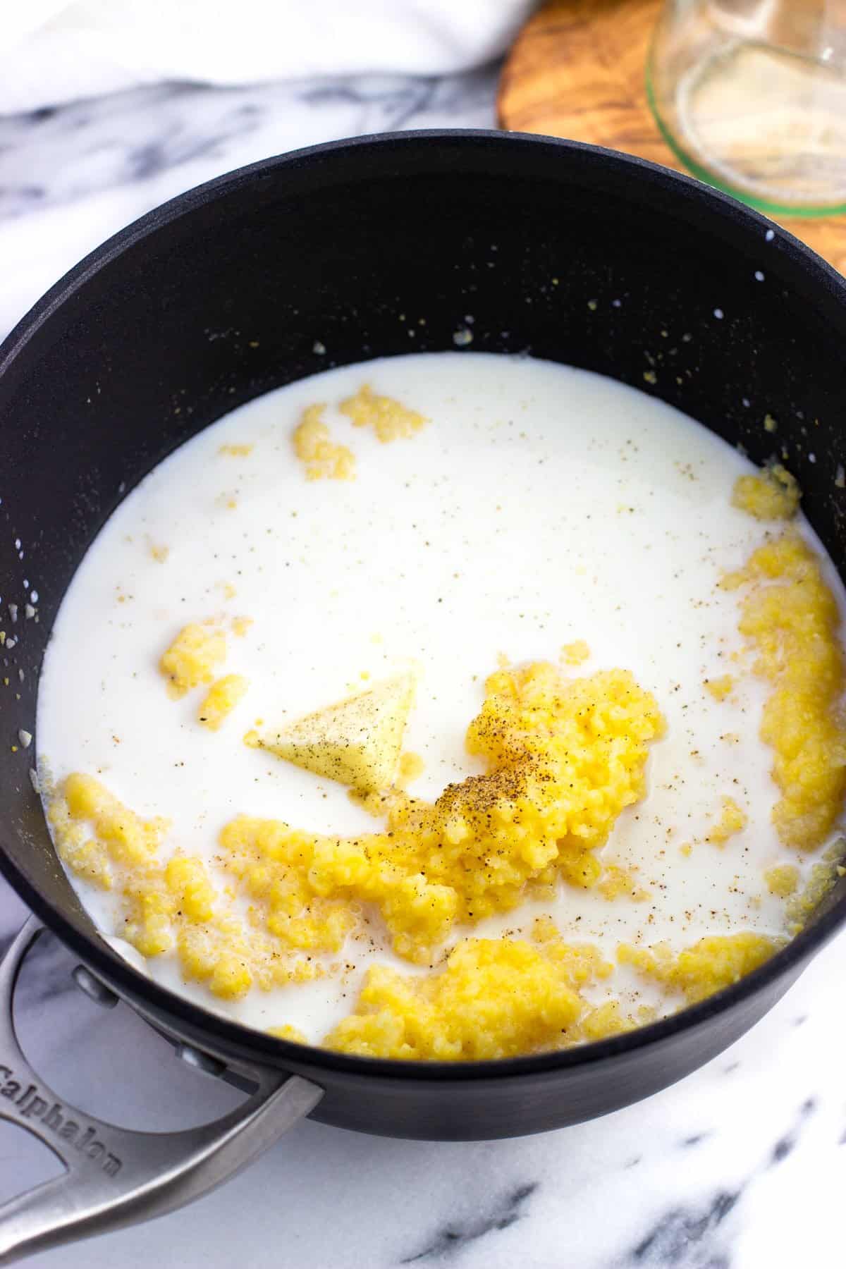 Milk, butter, and pepper poured into the pot of polenta.