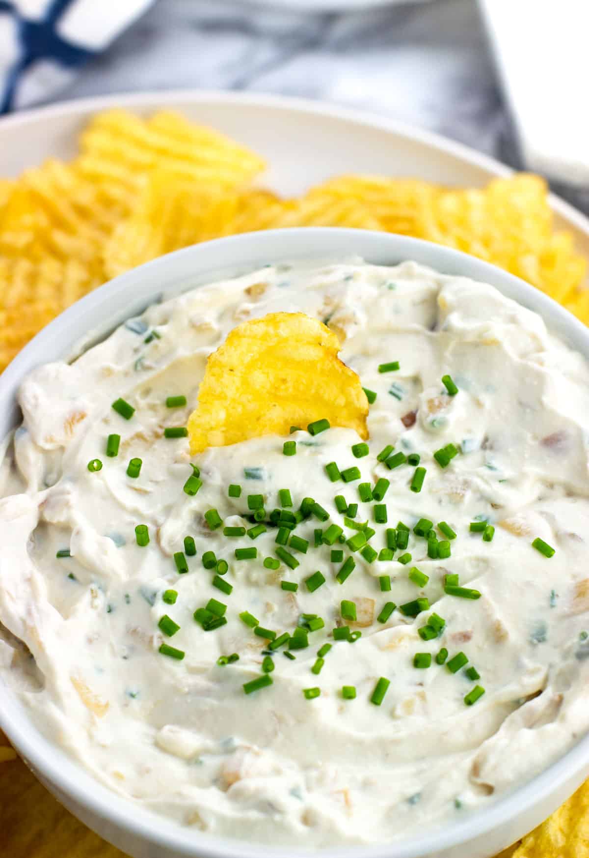 A chip being dipped into the bowl of french onion dip.