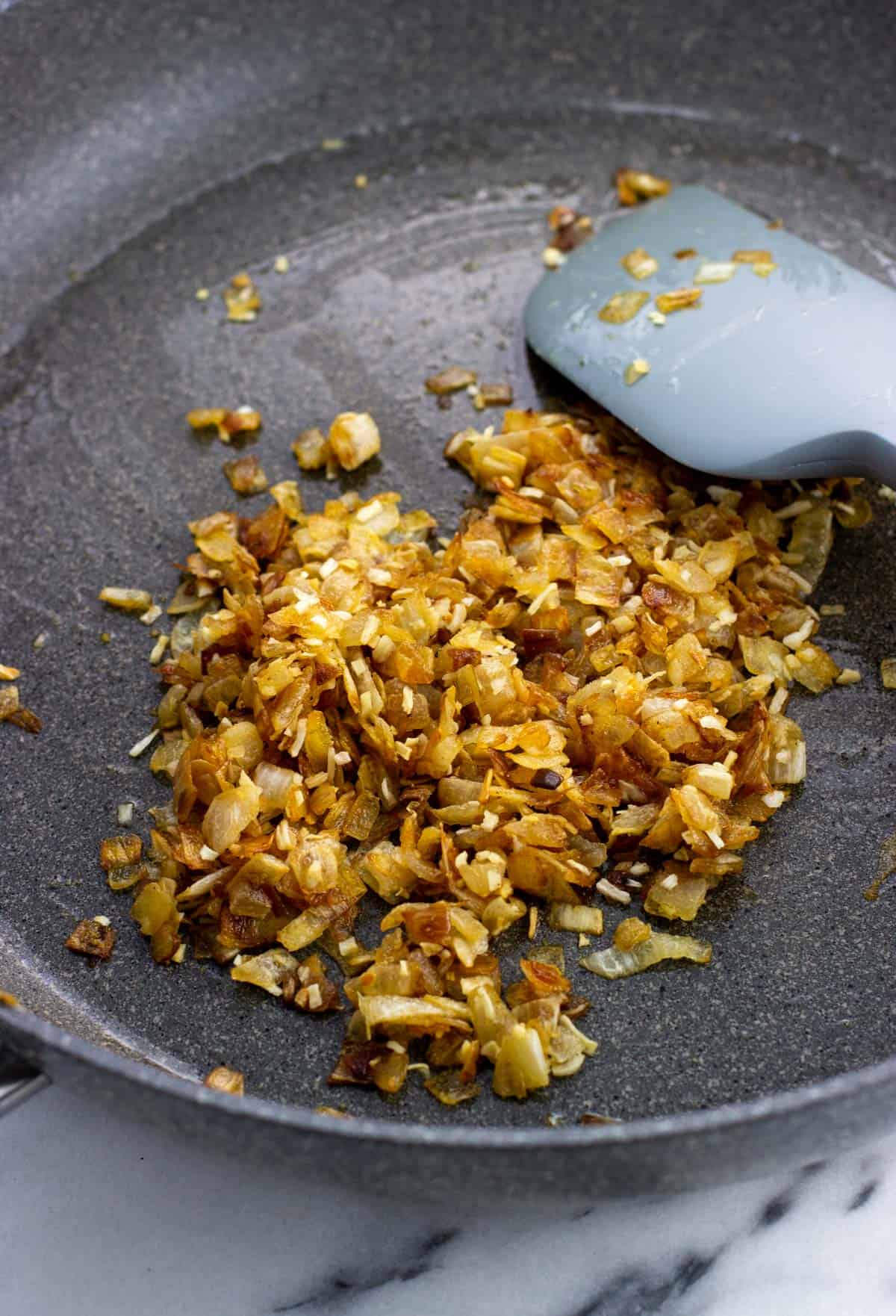 Caramelized diced onion mixed in a pan with dried onion flakes and garlic powder.