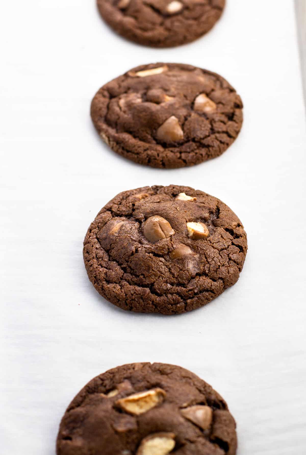 Baked Whoppers cookies on a parchment-lined baking sheet.