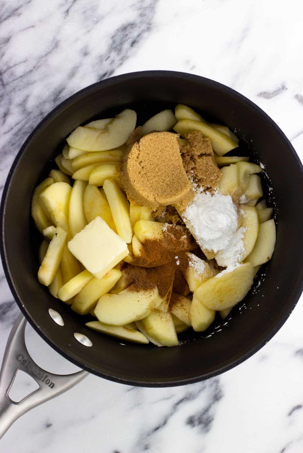 Sliced apples and the rest of the filling ingredients in a pan before cooking.