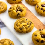 Baked pumpkin chocolate chip cookies on a serving board.