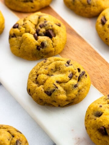 Baked pumpkin chocolate chip cookies on a serving board.