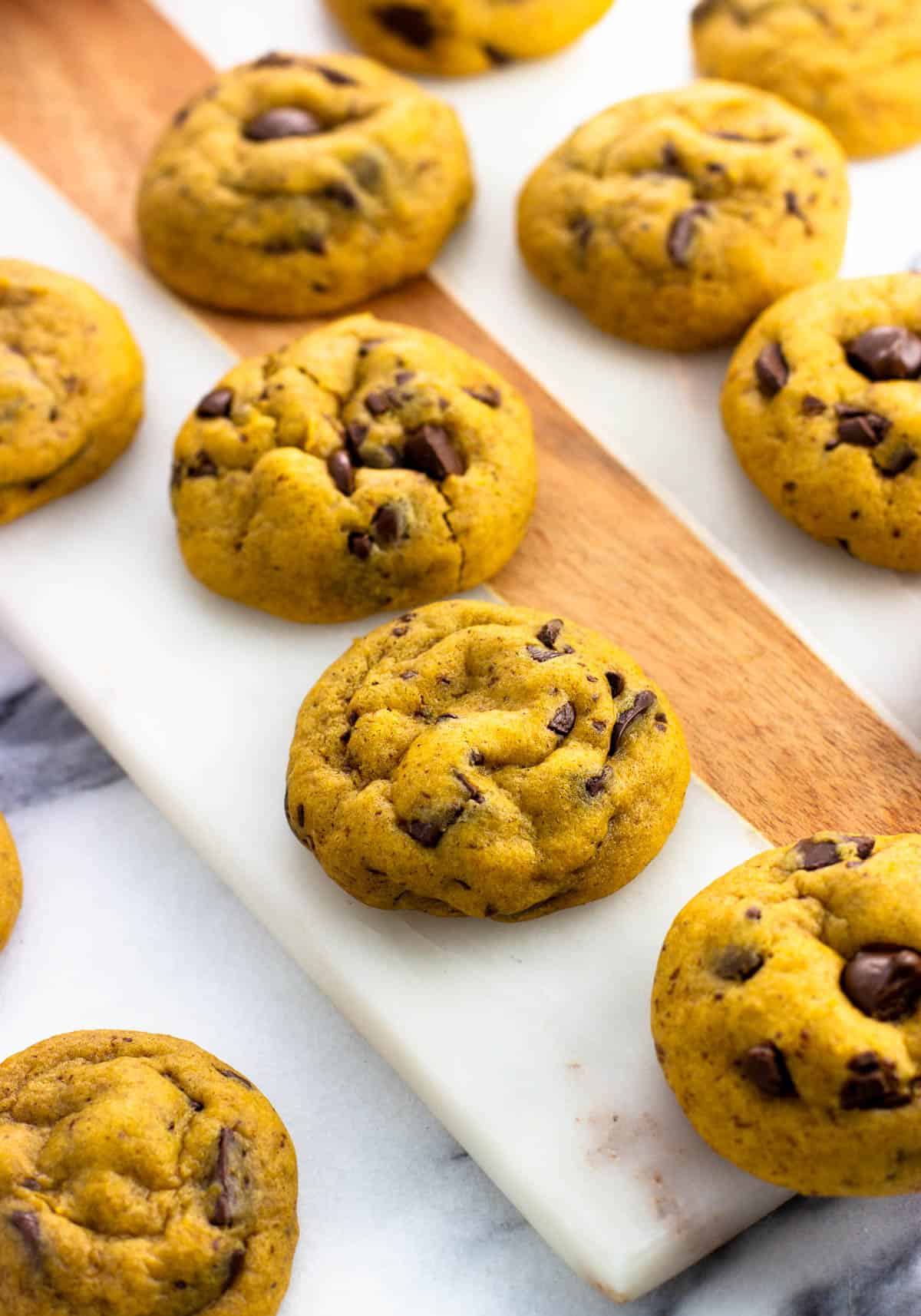 Baked pumpkin chocolate chip cookies on a serving board.