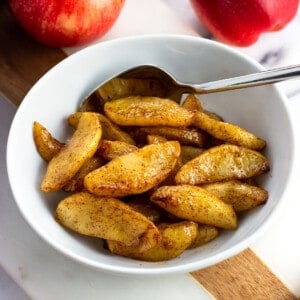 A small bowl of air fryer apples with a spoon.