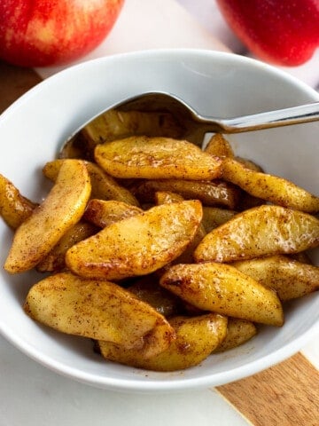 A small bowl of air fryer apples with a spoon.