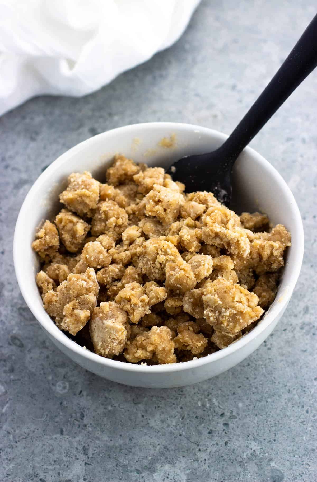 A bowl full of the mixed crumble topping with a spatula.