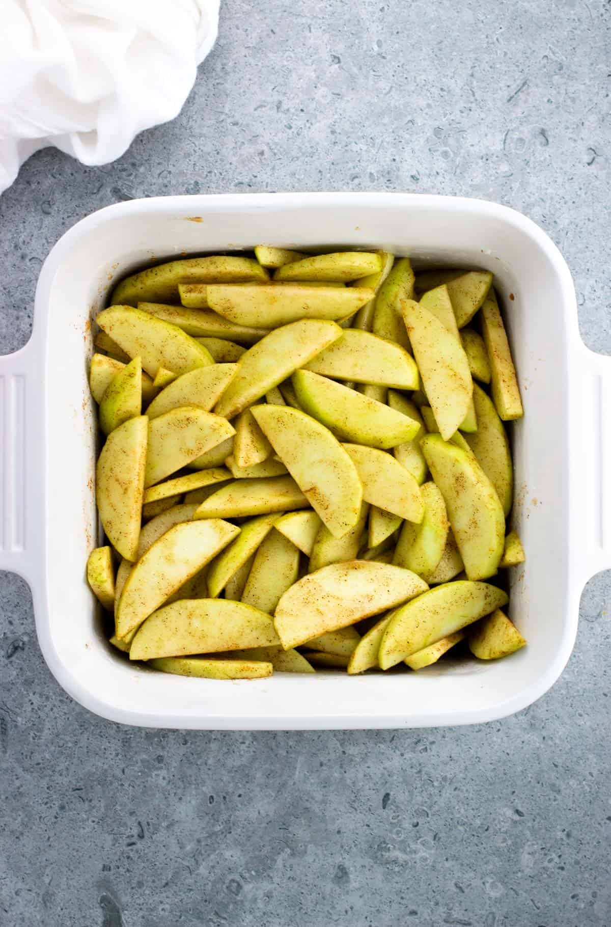 Apple slices in a square baking dish.