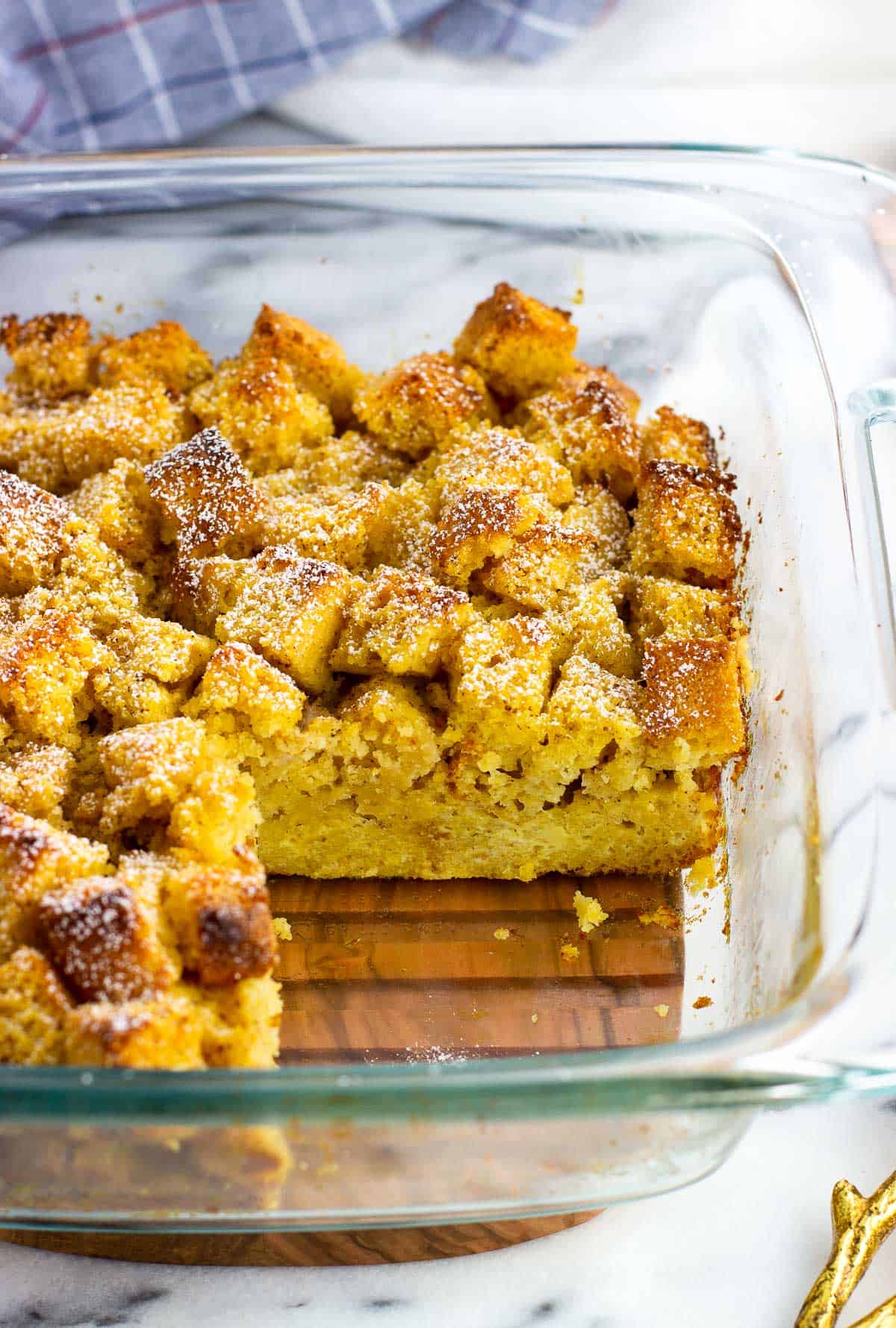 A side view of a pan of baked cornbread french toast with a wedge removed.