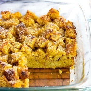 A side view of a pan of baked cornbread french toast with a wedge removed.