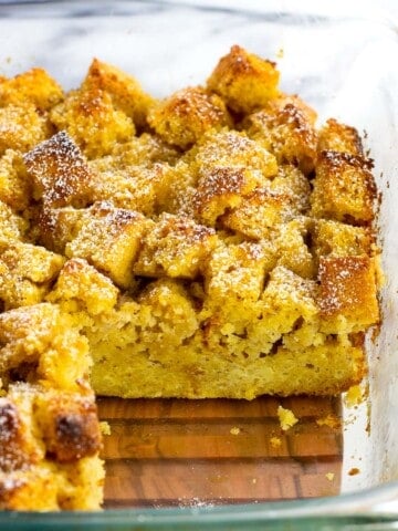 A side view of a pan of baked cornbread french toast with a wedge removed.