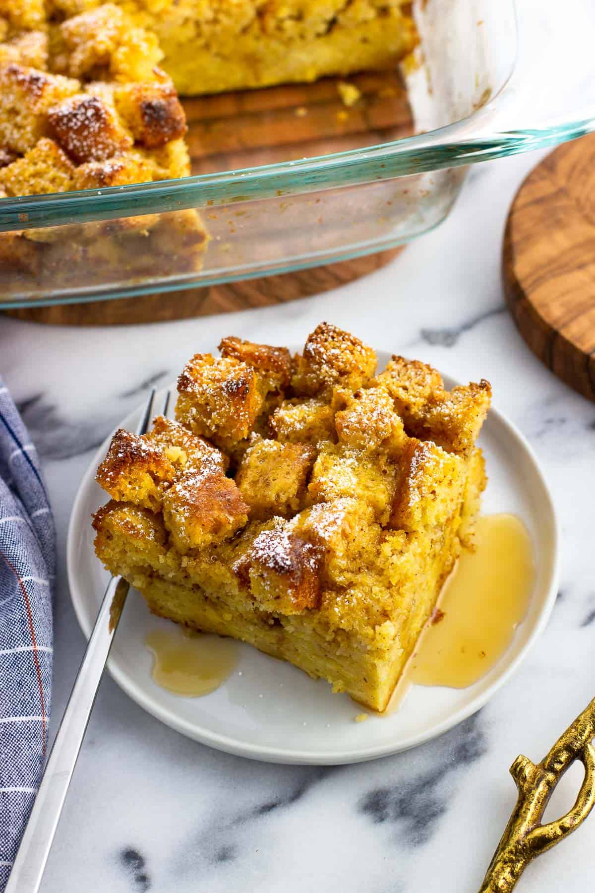 A square of french toast on a small plate drizzled with maple syrup.