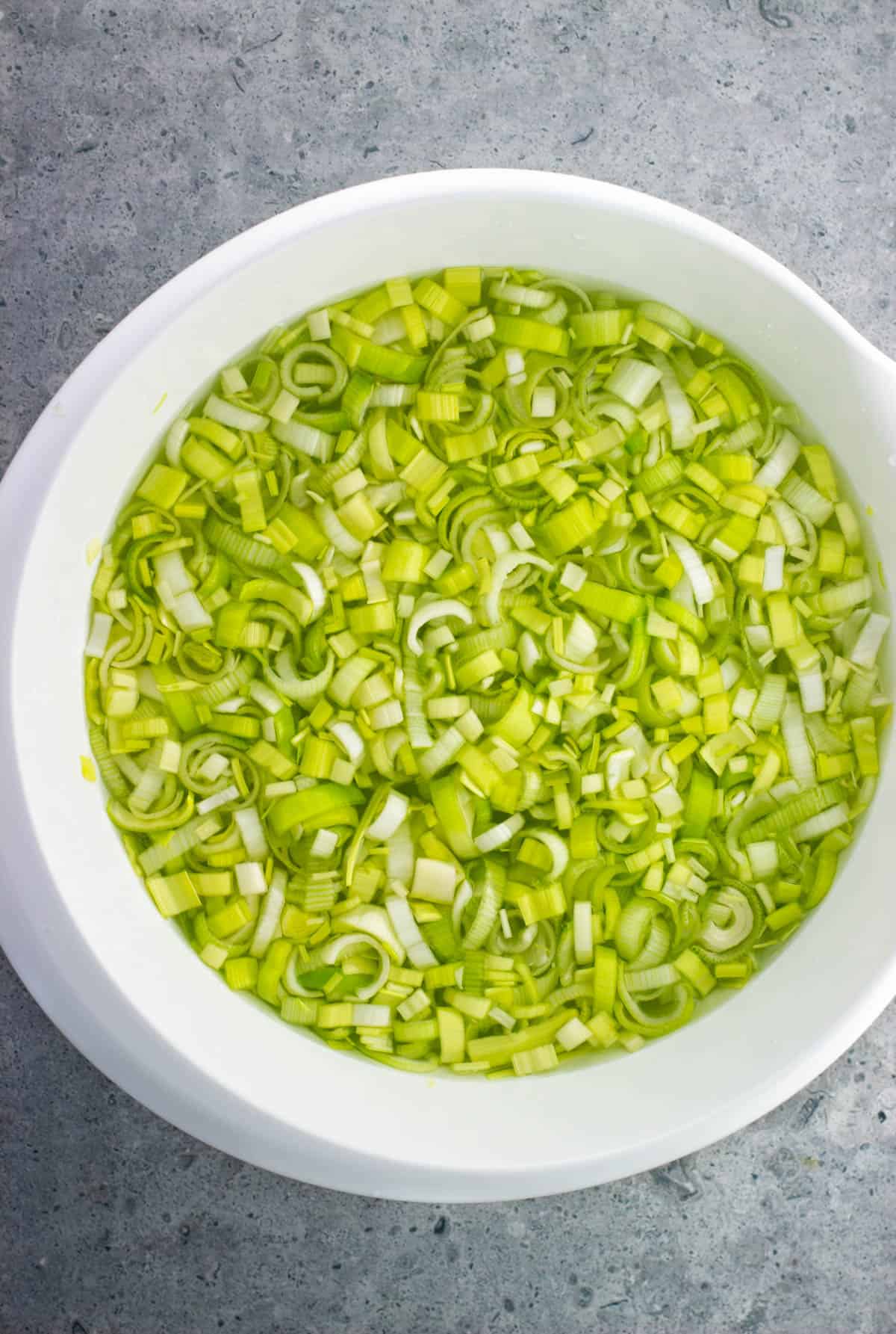 Sliced leeks in a large bowl of water.
