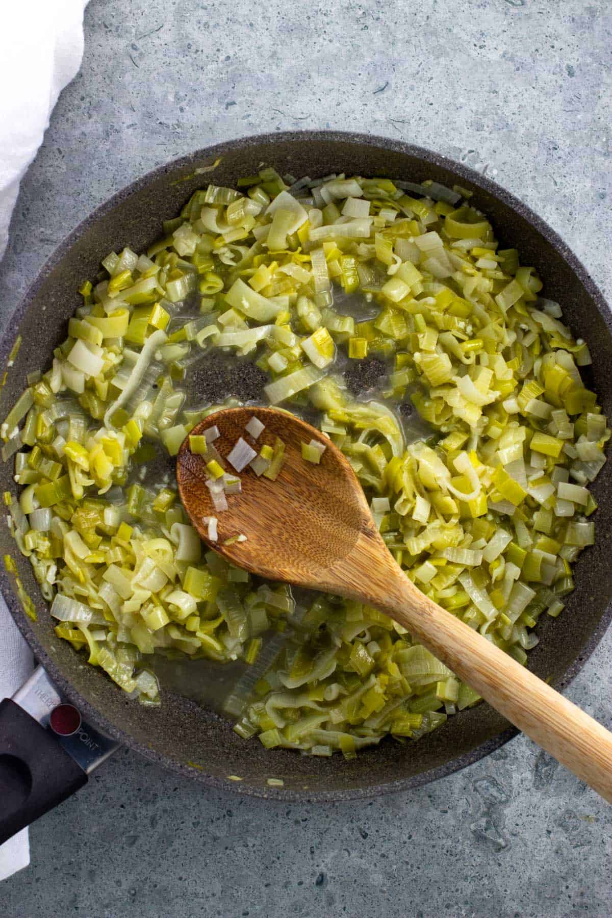 Sliced leeks in a pan after the broth and wine have reduced.