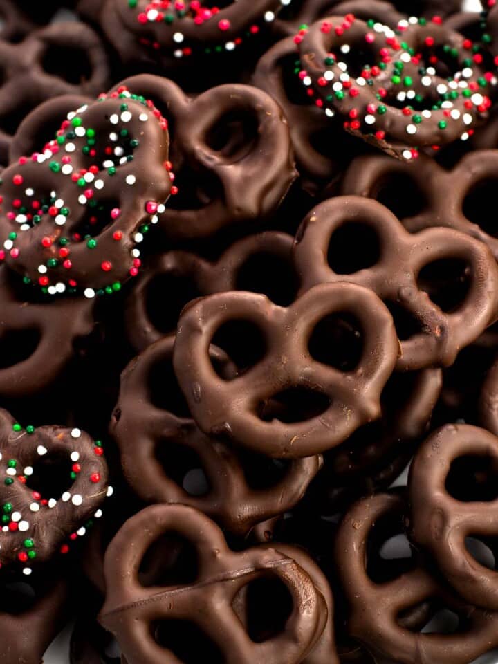A plate of dark chocolate peppermint pretzels, some covered in holiday red, white, and green sprinkles.