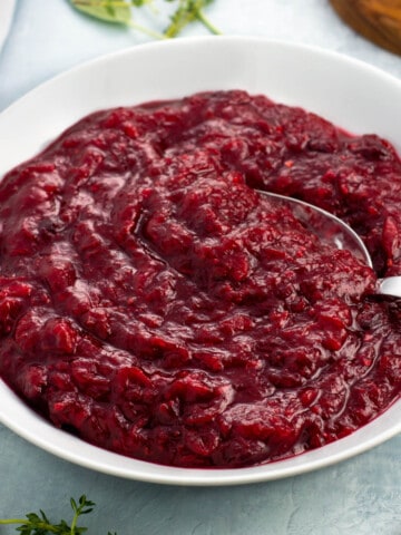 A serving spoon in a bowl of cranberry sauce.