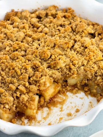 A serving dish of pear crumble with a big scoop removed.