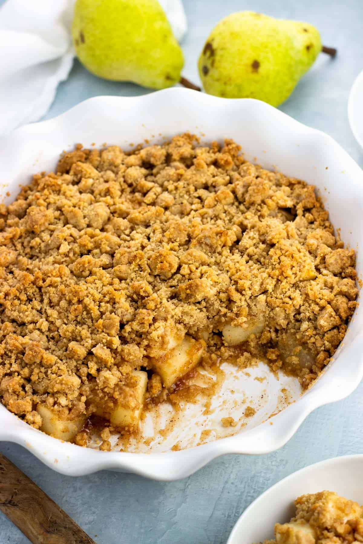 A serving dish of pear crumble with a big scoop removed.