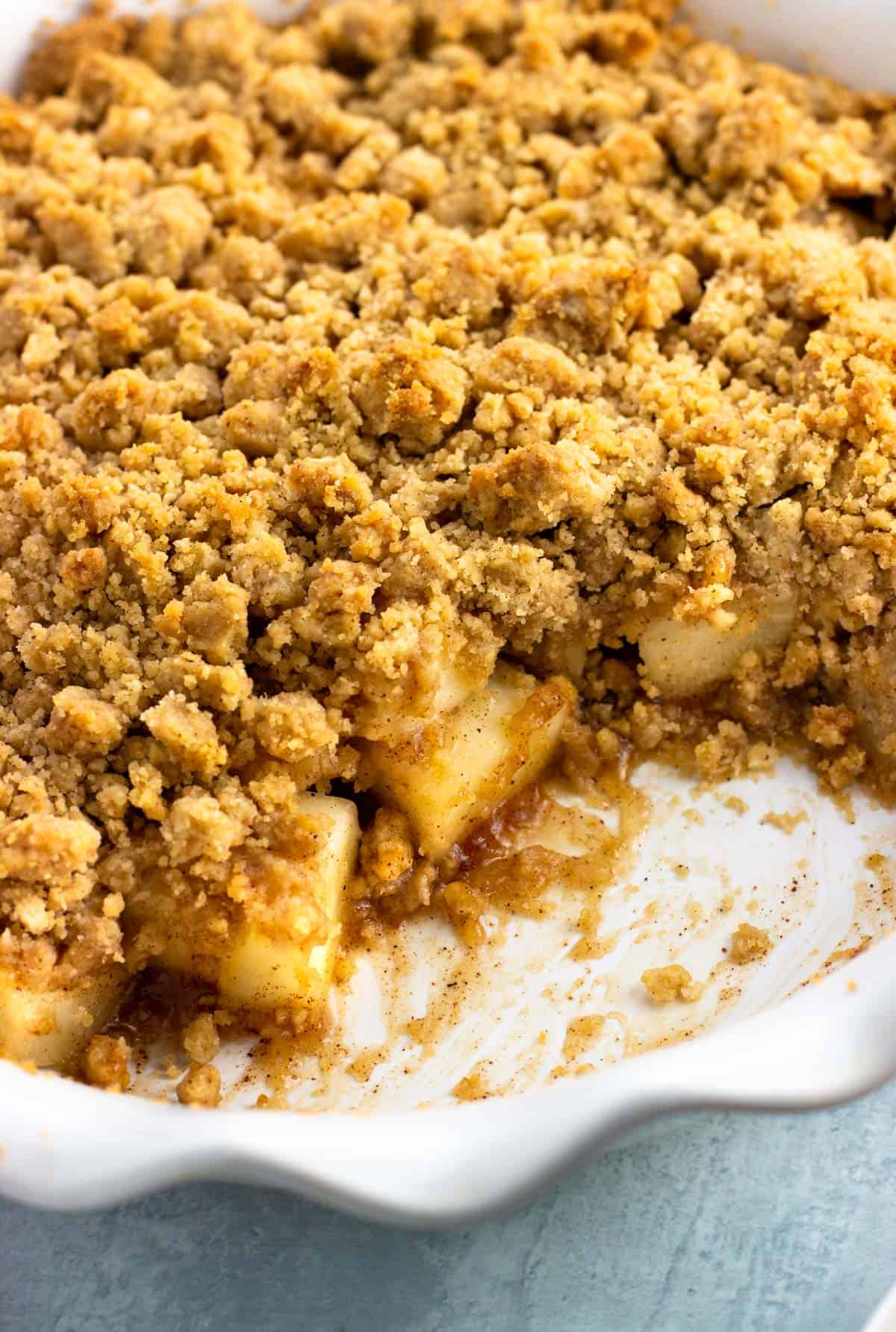 A close-up of the layers of pear crumble, including gooey fruit and golden brown and crisp topping.