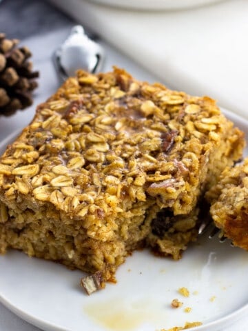 A square of eggnog oatmeal on a small plate with a bite removed.