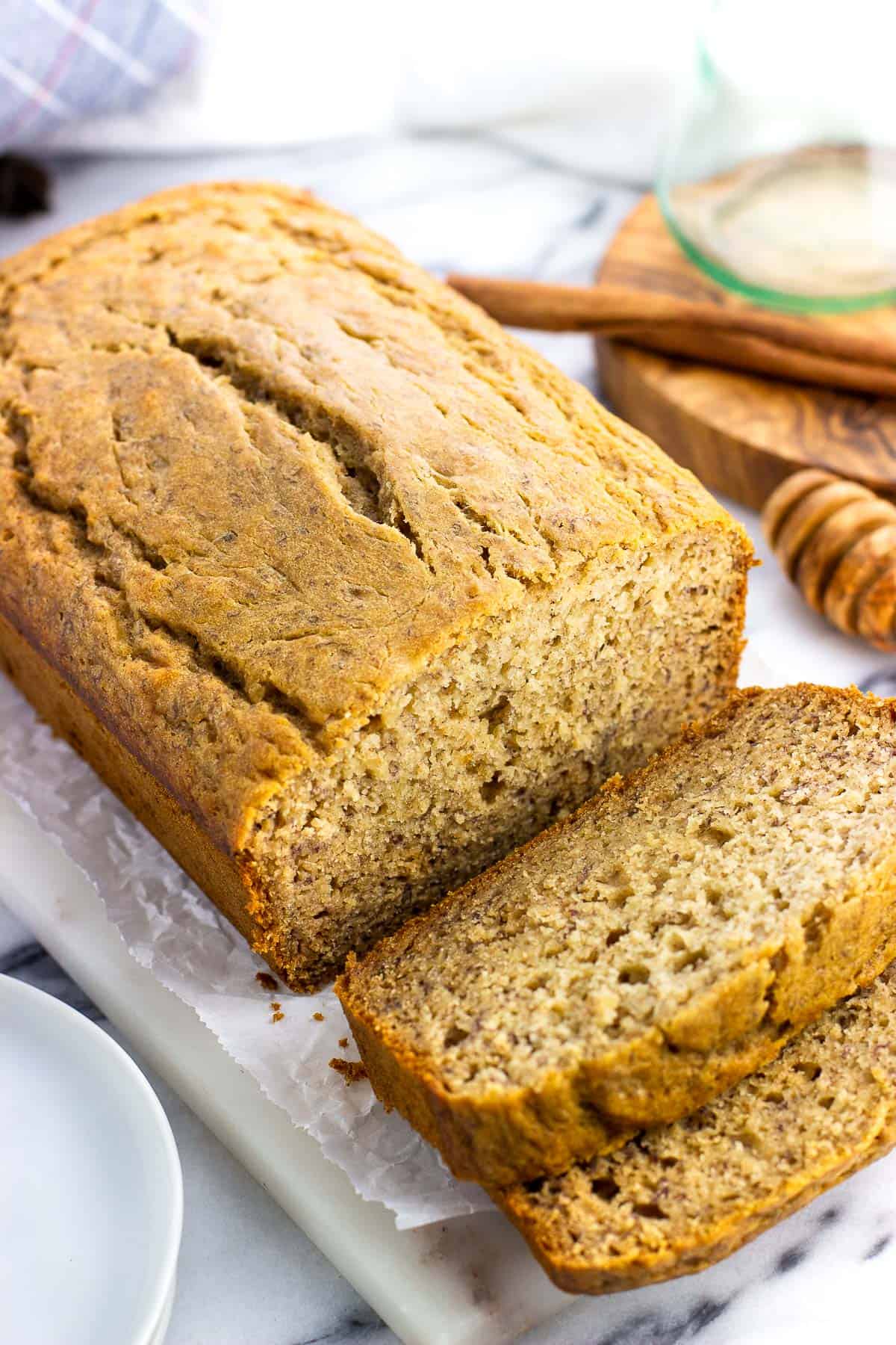 A loaf of honey banana bread on a serving tray with two pieces sliced from one end.