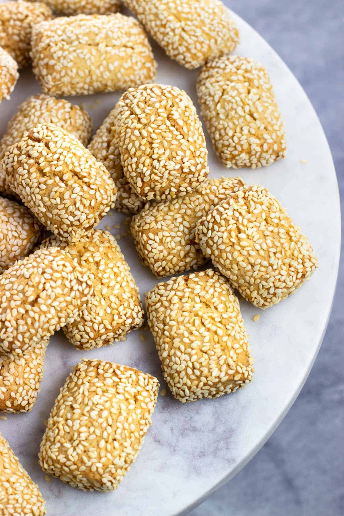 Italian sesame cookies on a round marble cake stand for serving.