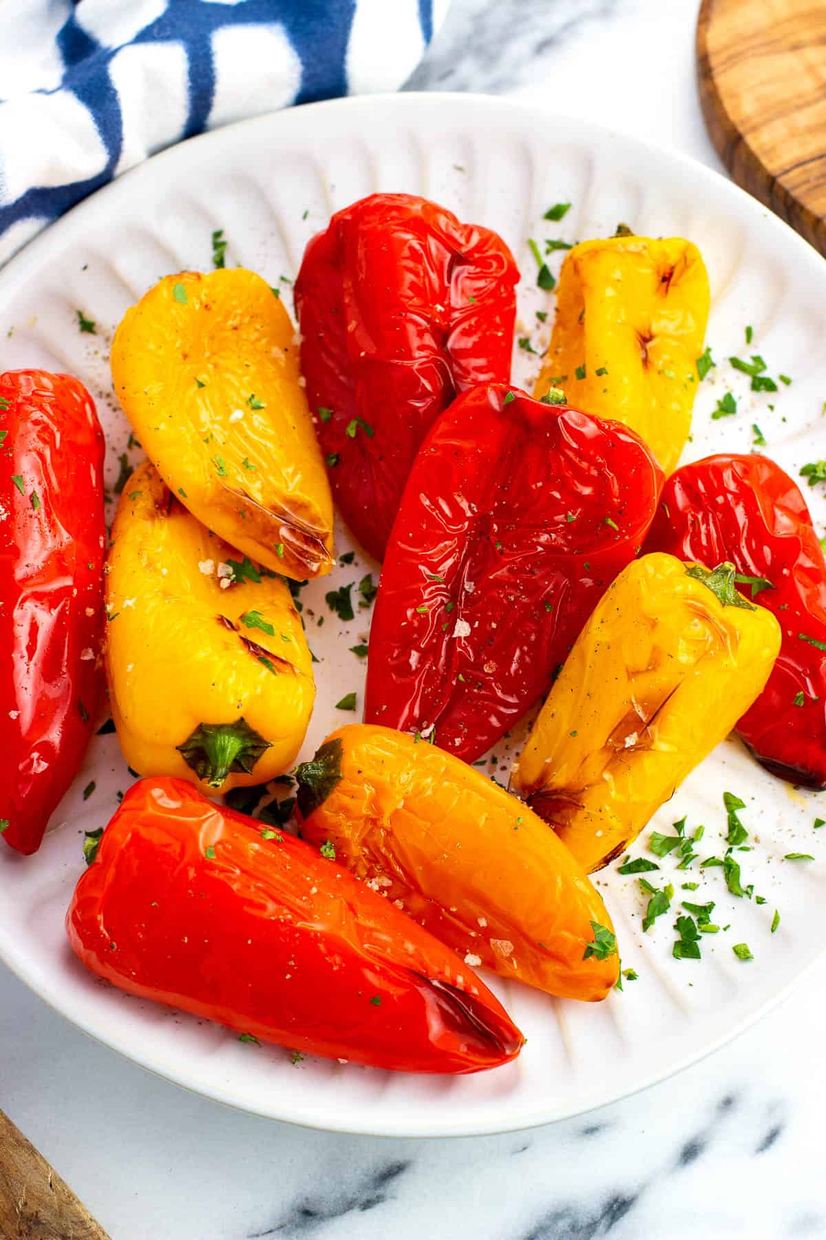Air fried mini sweet peppers on a plate garnished with fresh herbs and flaky salt.