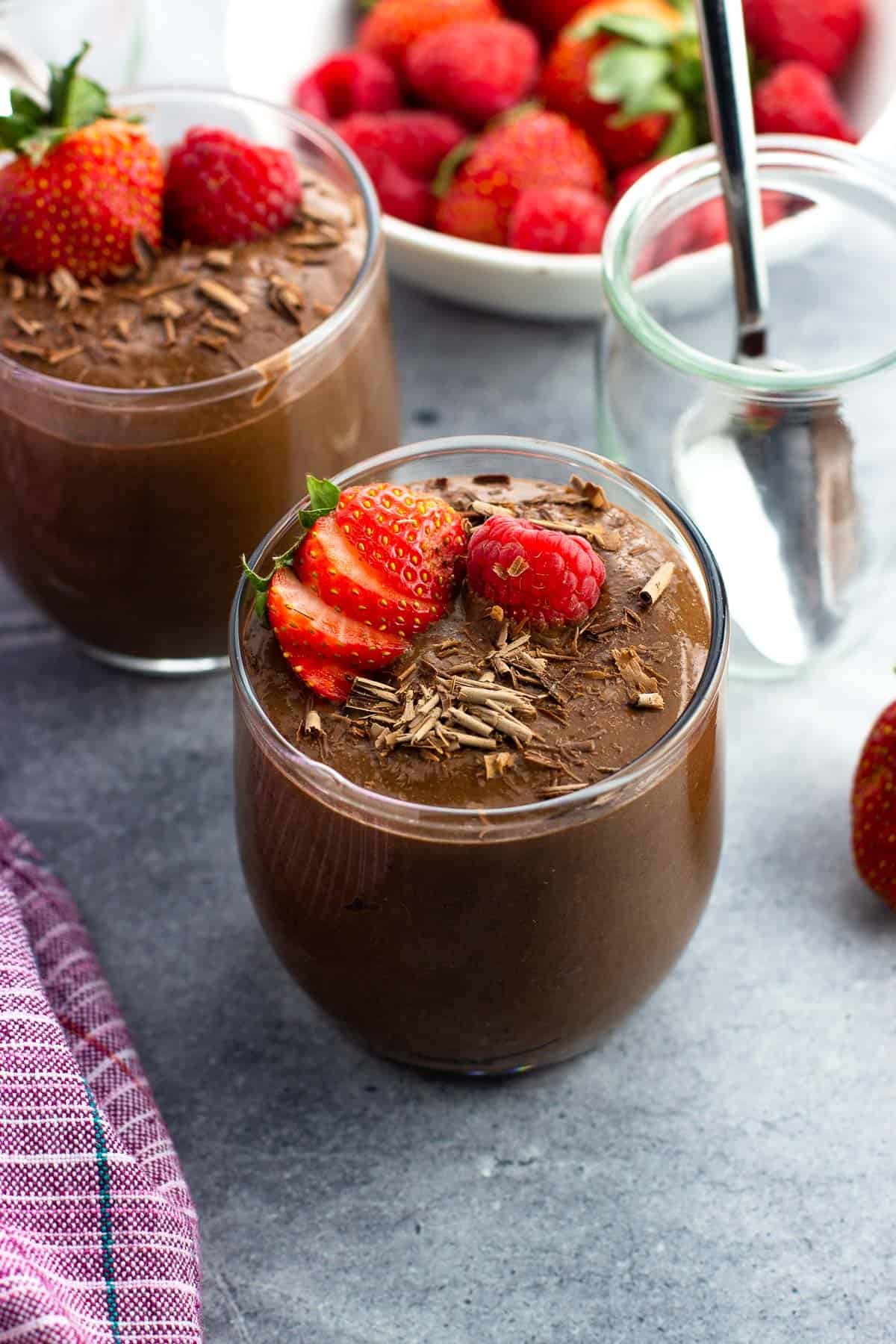 Chocolate chia seed pudding cups topped with strawberries and raspberries.