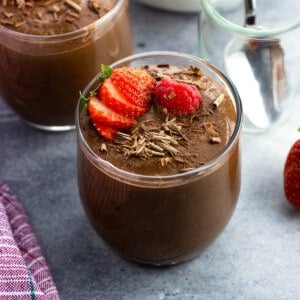 Chocolate chia seed pudding cups topped with strawberries and raspberries.