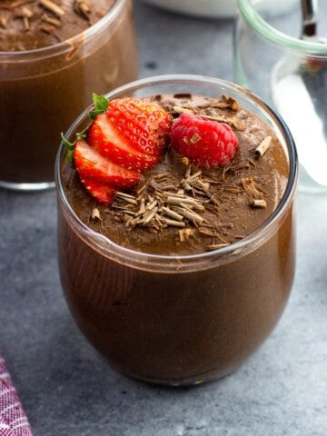 Chocolate chia seed pudding cups topped with strawberries and raspberries.