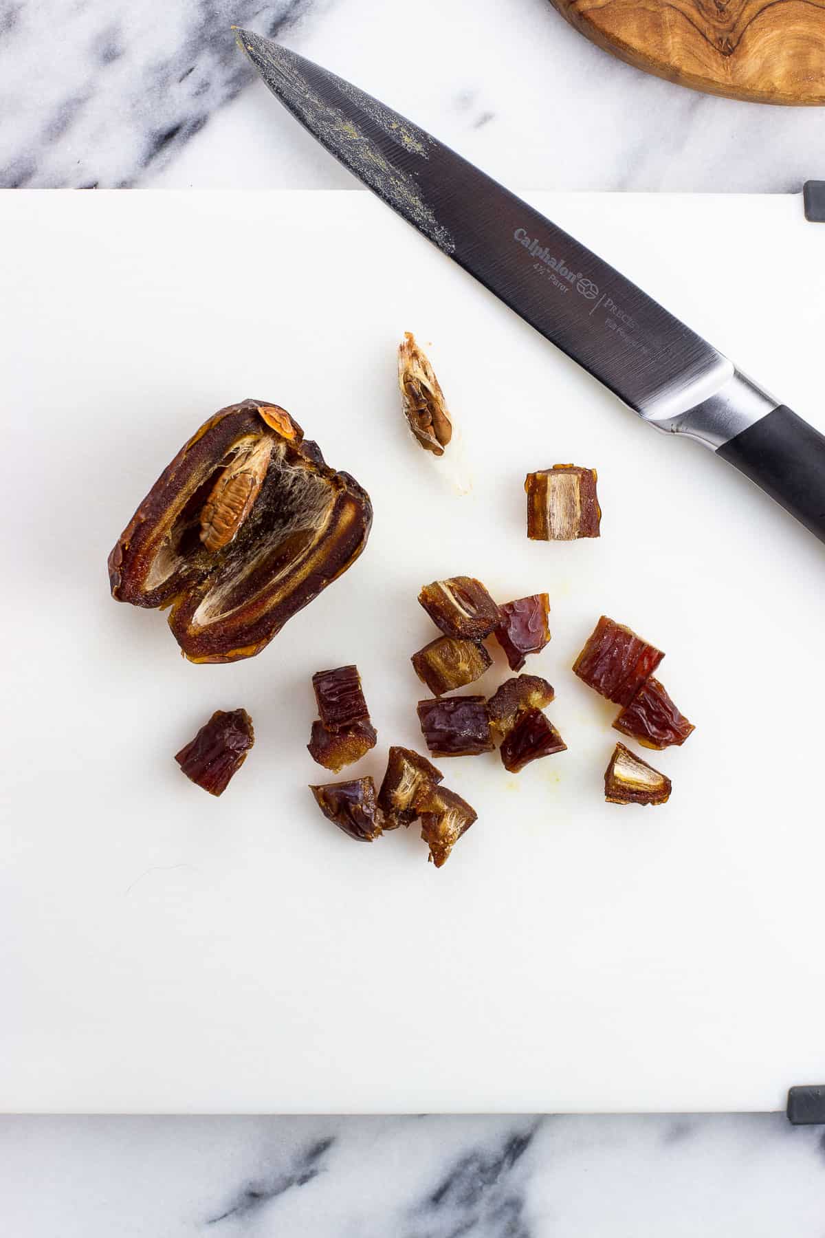 Dried dates on a cutting board being roughly chopped.