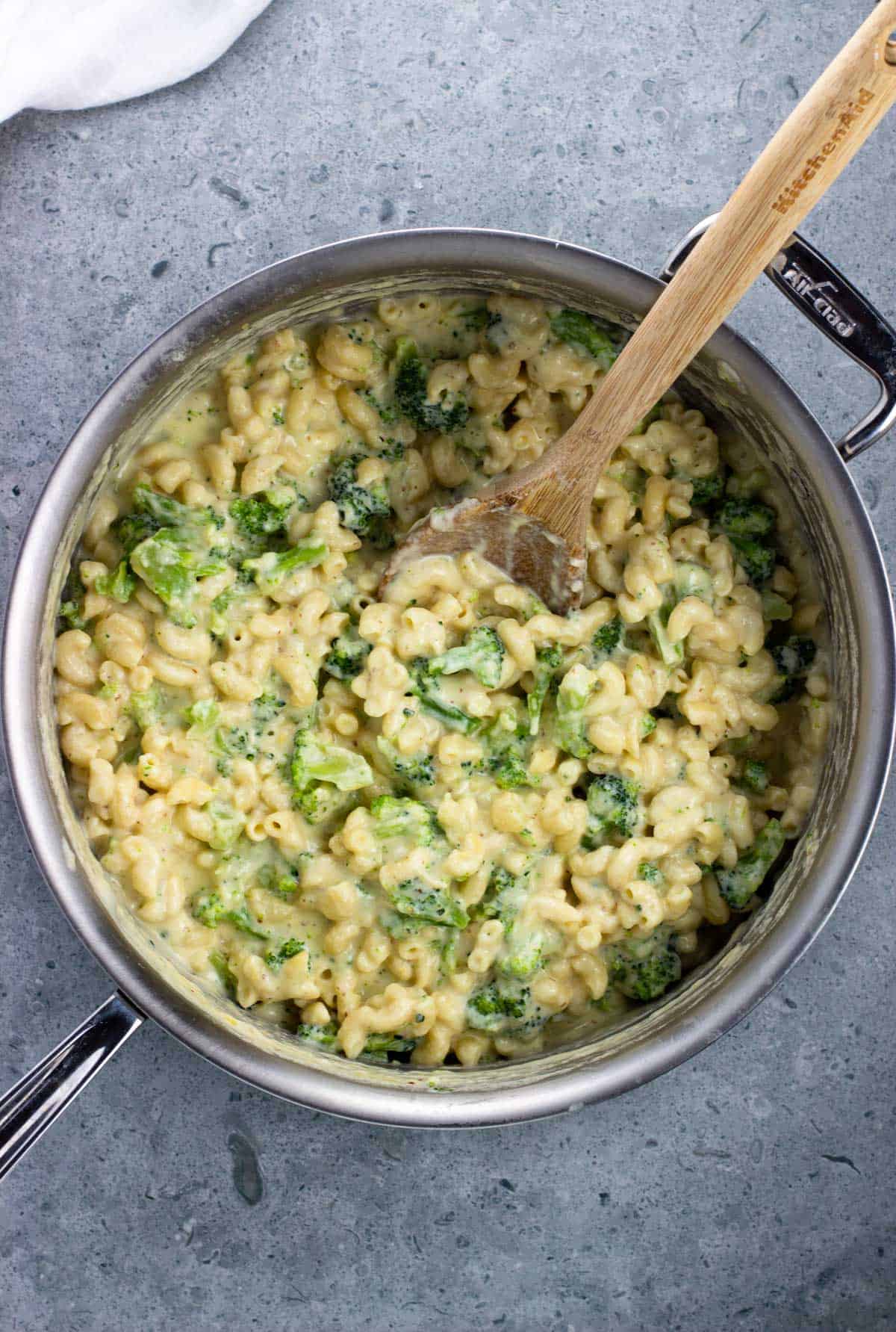 A pot of protein mac and cheese with a wooden spoon in it.