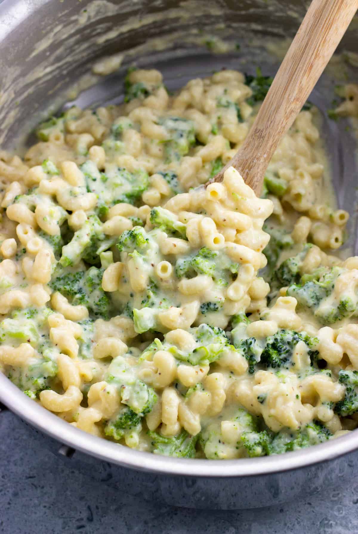 A spoon scooping a serving of mac and cheese out of the pot.