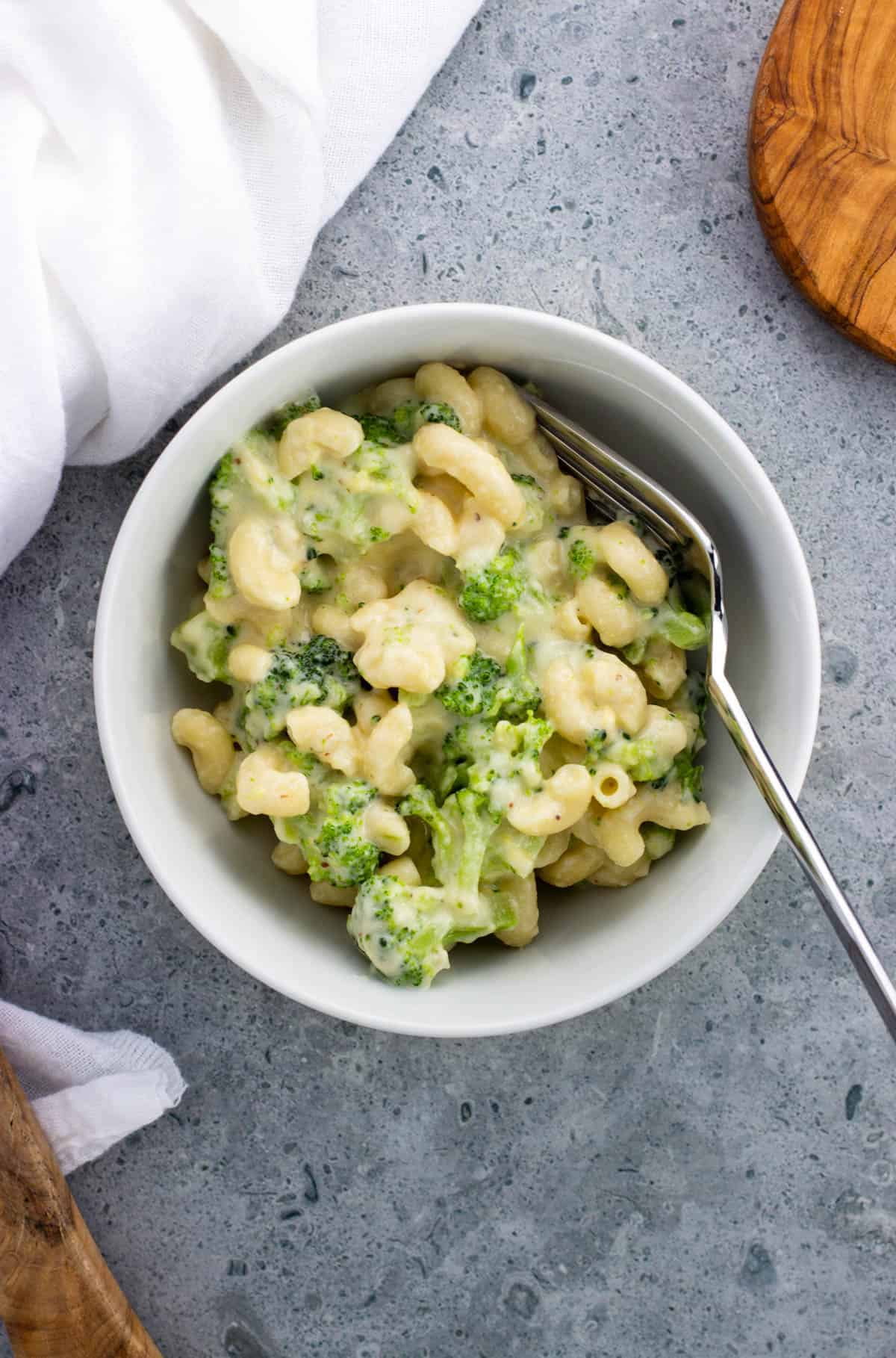 A bowl of mac and cheese and broccoli with a fork in it.