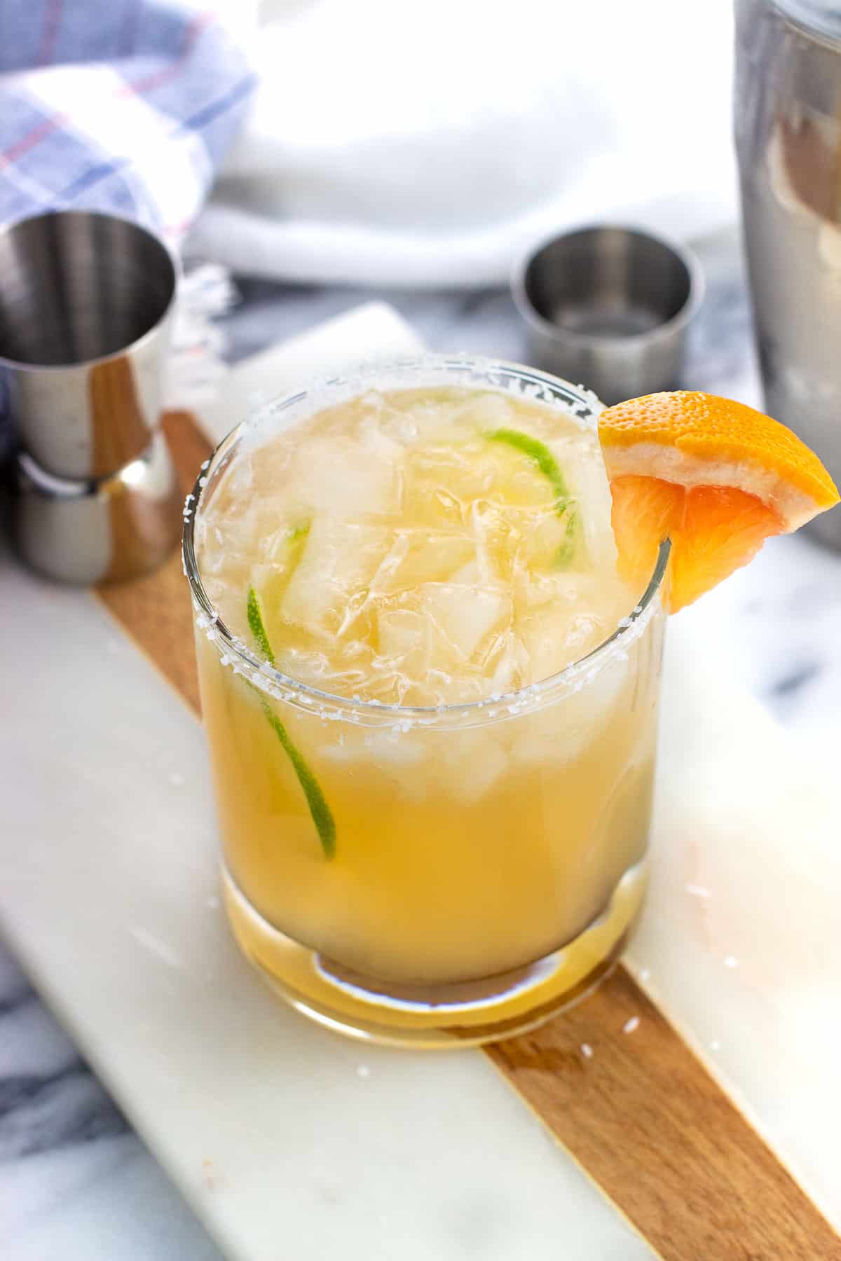 A paloma mocktail in a short salt-rimmed glass garnished with lime rounds and a grapefruit wedge.