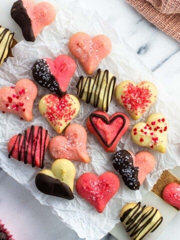 Heart-shaped spritz cookies on a sheet of crinkled parchment paper.