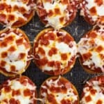 Mini pepperoni pizza bagels cooked on an air fryer basket.