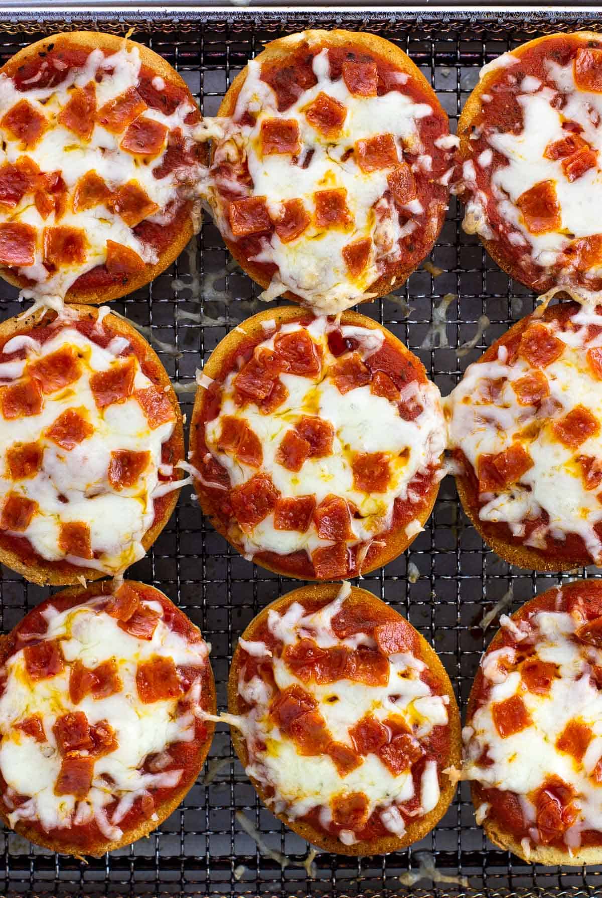 Mini pizza bagels in an air fryer basket.