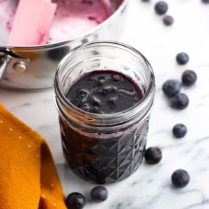 A glass jar of blueberry maple syrup.