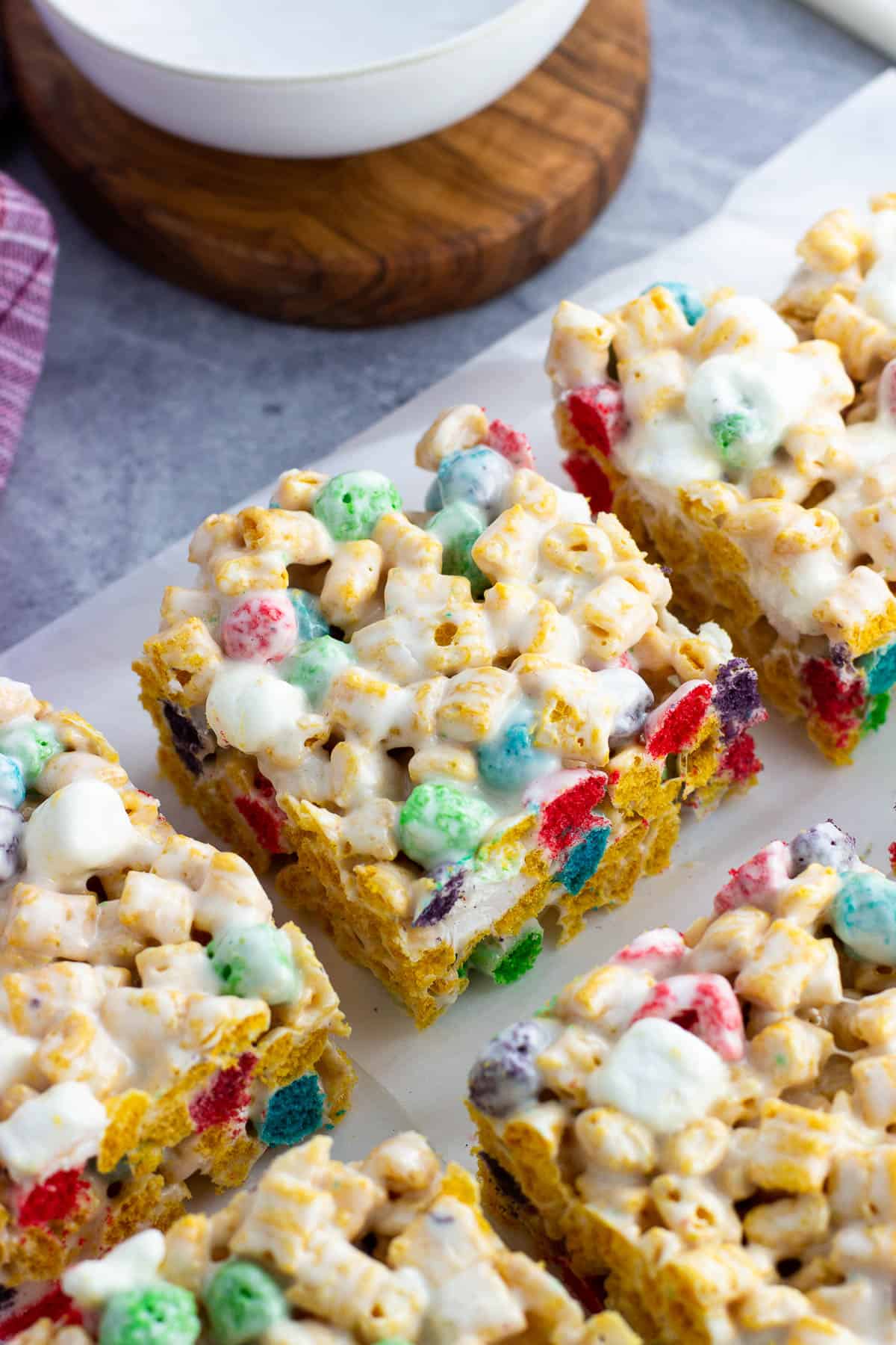 Squares of Cap'n Crunch cereal bars (with berries) on a sheet of parchment paper.