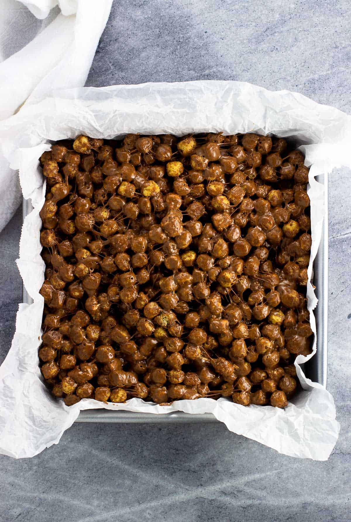 Chocolate Peanut Butter Cap'n Crunch Treats pressed into a parchment-lined square pan.