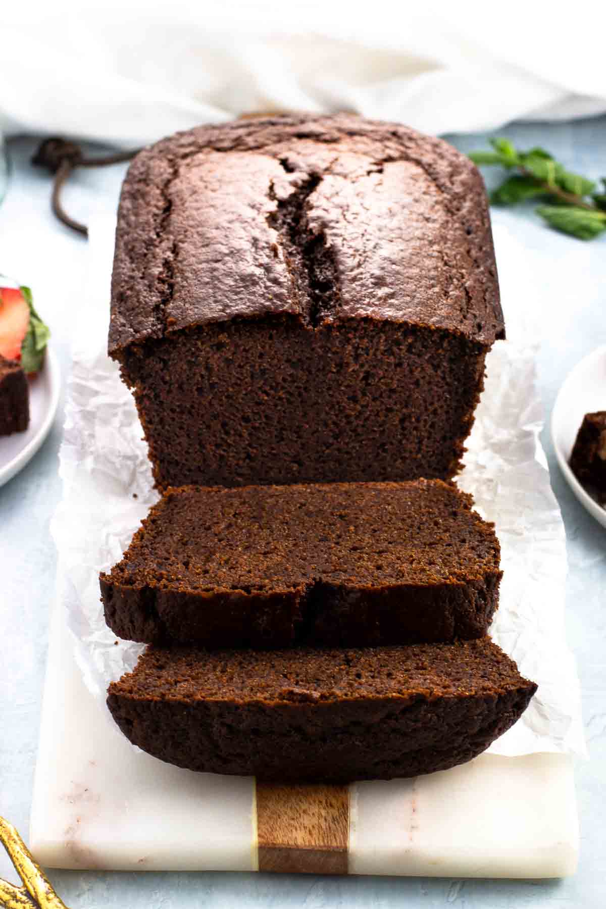 A straight-on view of a partially-sliced chocolate yogurt cake loaf.