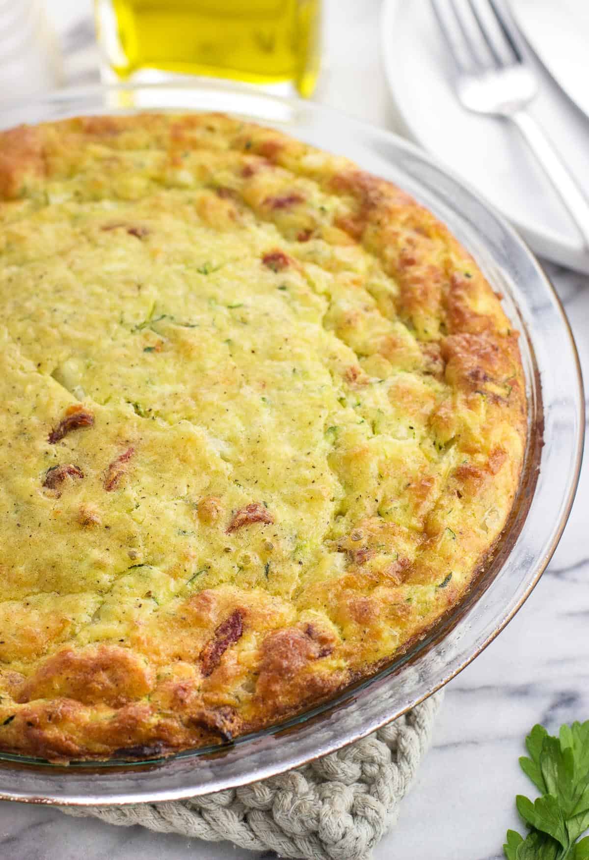 Browned and puffed up zucchini pie in a glass pie plate.