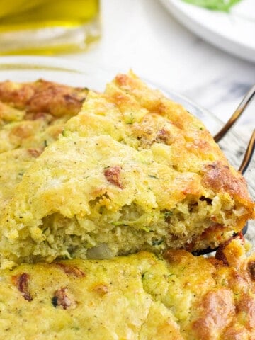 A wedge of zucchini pie being lifted out of the pan with a spatula.