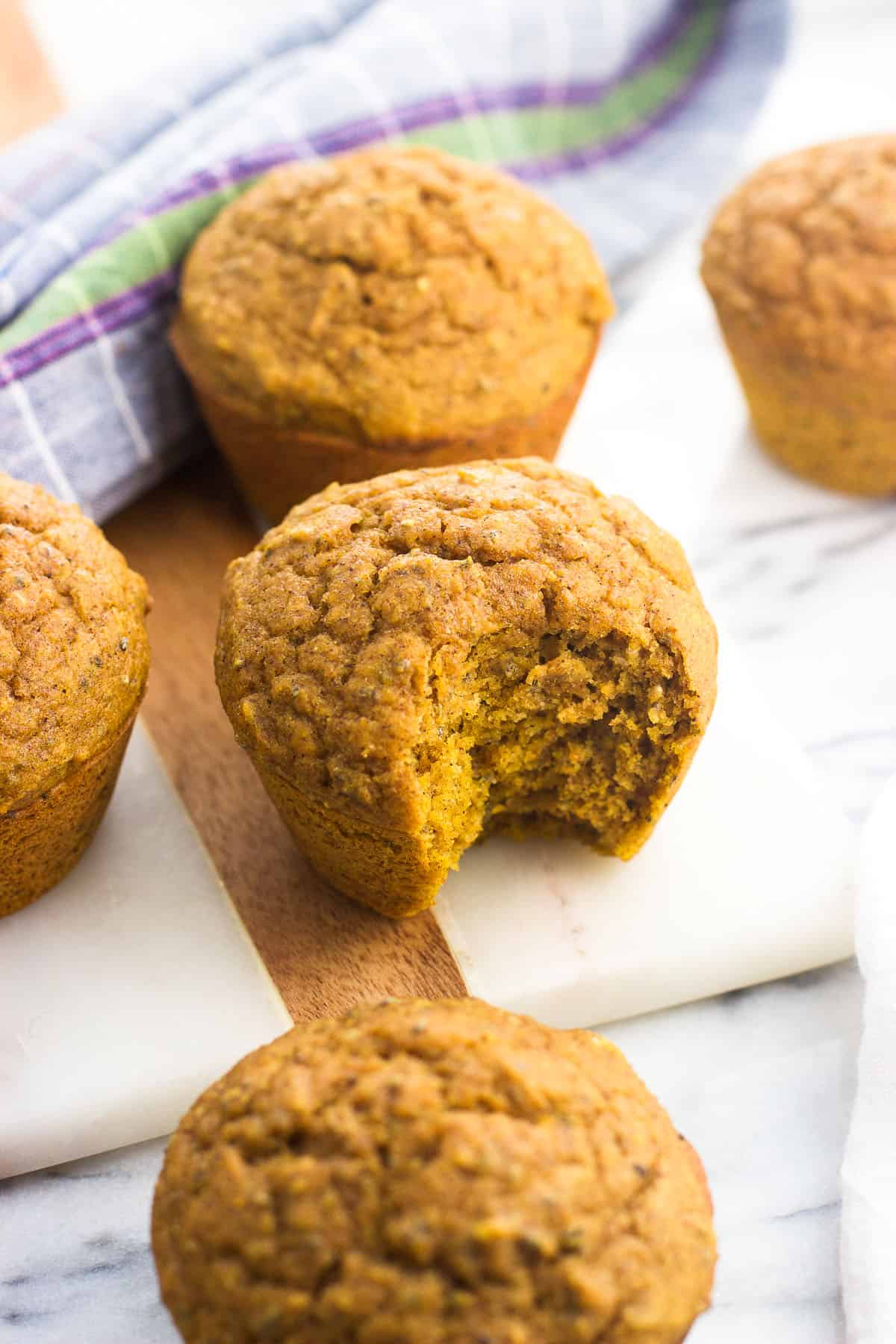Pumpkin muffins on a serving board with a bite taken out of one.