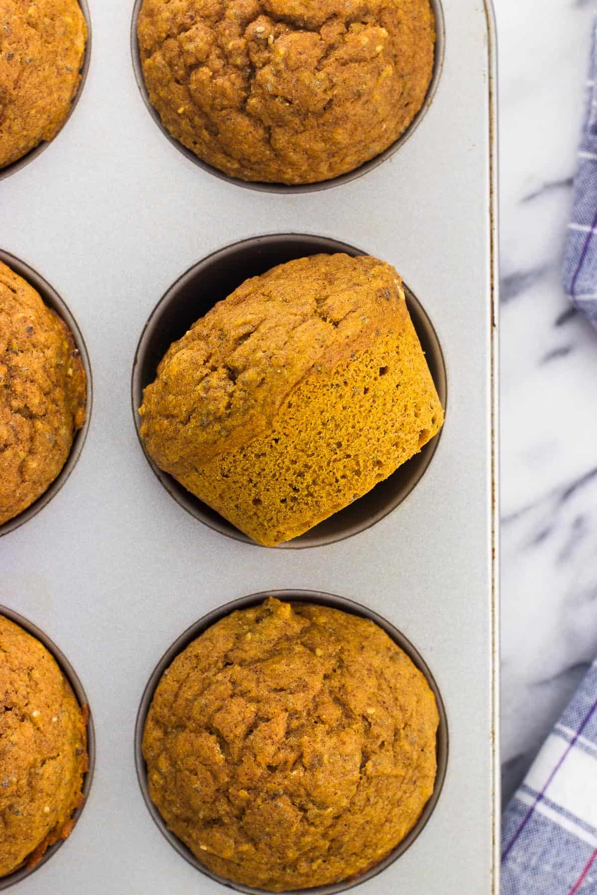 Baked pumpkin muffins in a metal muffin tin.