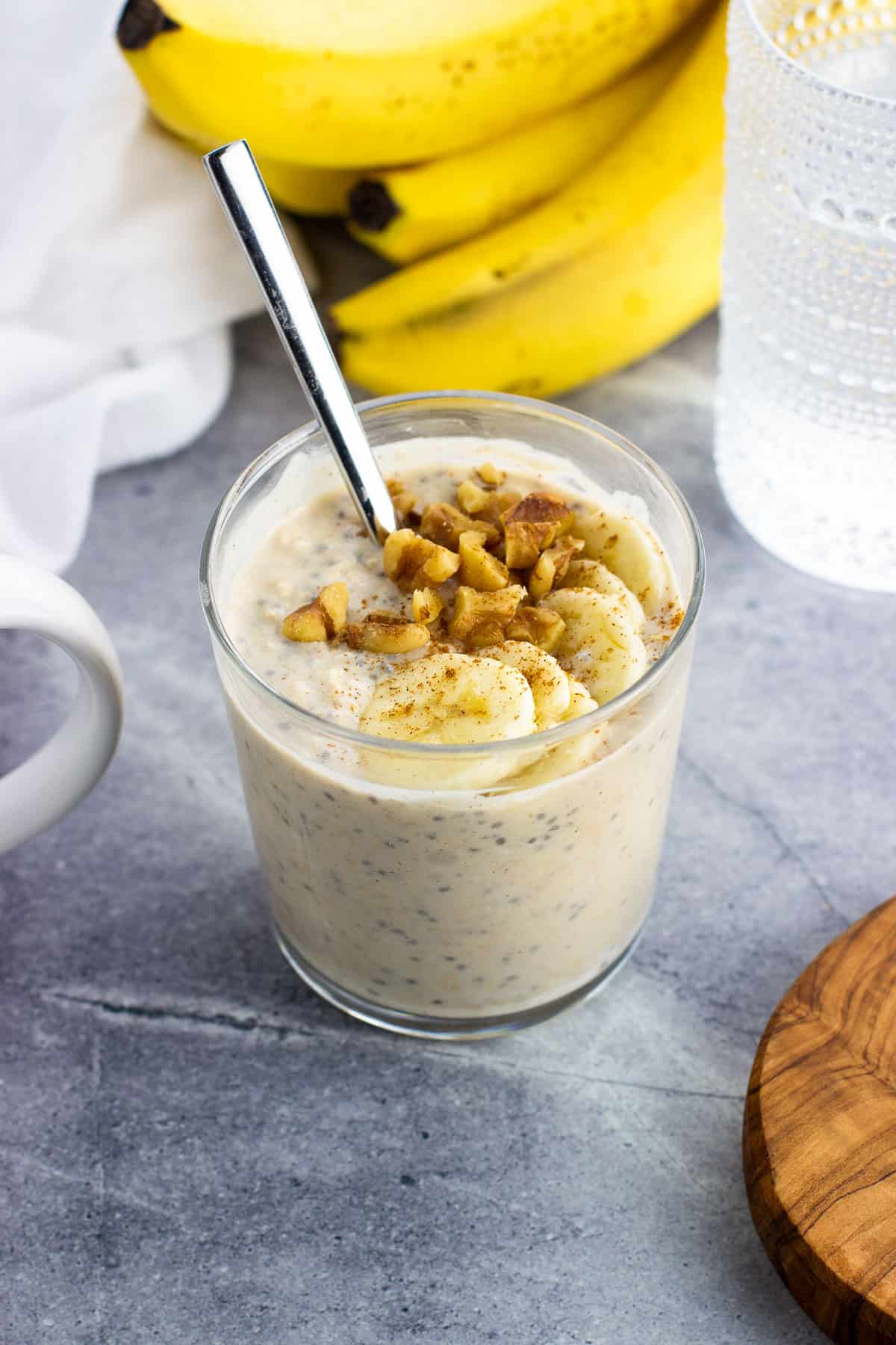 A short glass of protein overnight oats topped with walnuts and banana slices.